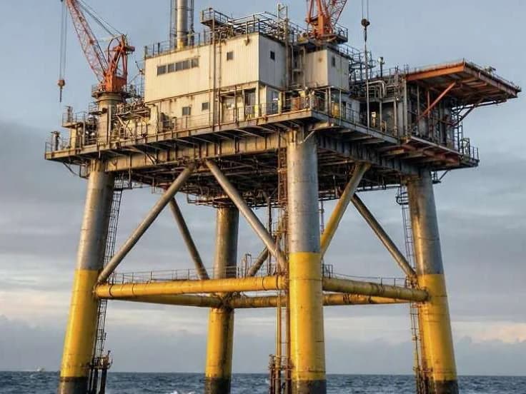 Fixed-leg offshore platform with cranes and process equipment above the sea