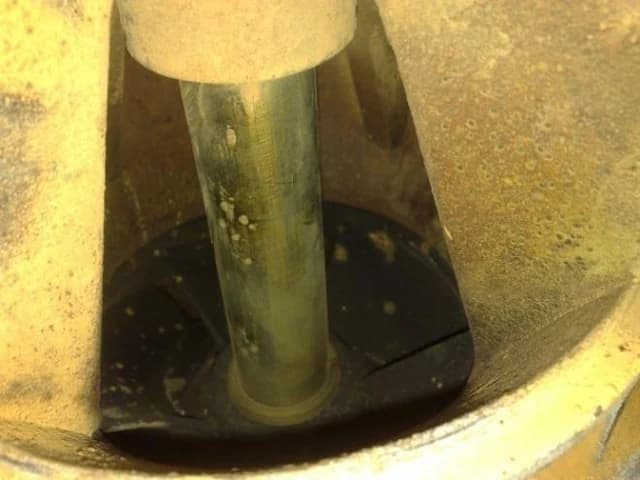 Close-up of a dismantled deep-well pump showing pitting on the blade beside its shaft