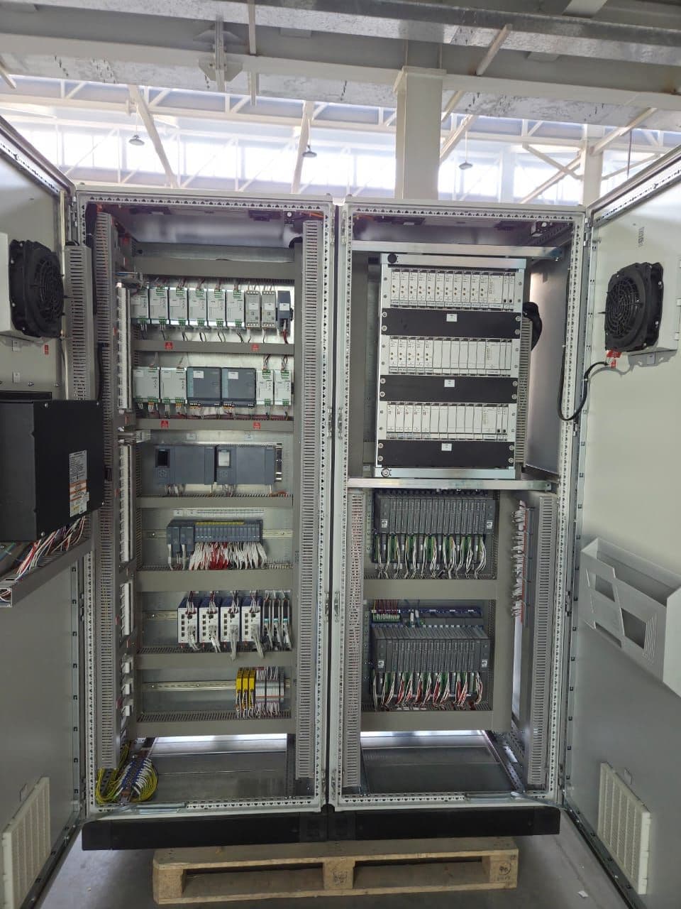 Interior of a NATCOM control cabinet showing PLC modules, wiring, and I/O cards