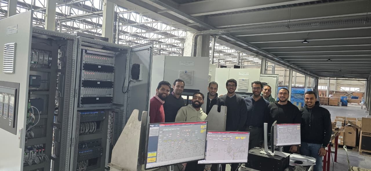 The NATCOM engineering team during Factory Acceptance Testing with HMI screens and control panels
