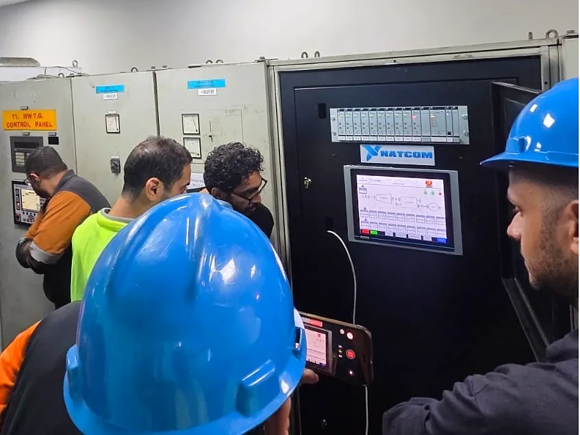 Engineers in hard hats at the new NATCOM vibration monitoring cabinet and HMI during site commissioning