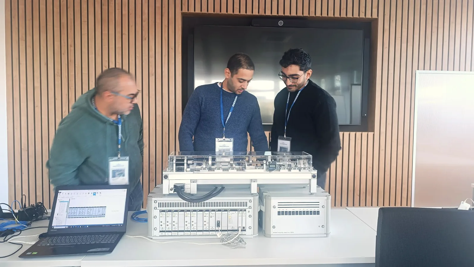 Three engineers around an Emerson AMS 6500 ATG rack and test rig during Factory Acceptance Testing